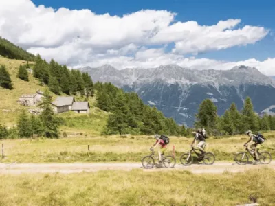 Graubünden – Mountainbiker in alpiner Landschaft mit Bergen und Almhütten